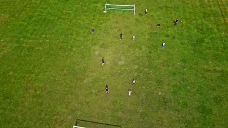 adults and kids playing football outdoors - aerial, static shot