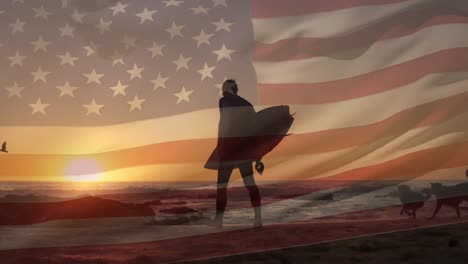 Zusammengesetztes-Video-Einer-Schwenkenden-Amerikanischen-Flagge-über-Der-Rückansicht-Eines-Mannes,-Der-Mit-Einem-Surfbrett-Am-Strand-Spaziert