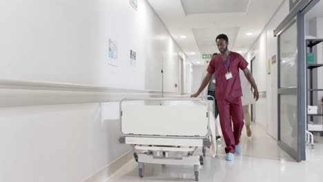 Focused-african-american-male-nurse-walking-with-hospital-bed-in-slow-motion,-unaltered