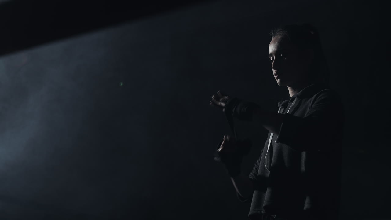 Young woman preparing for training in a dramatic, smoky environment