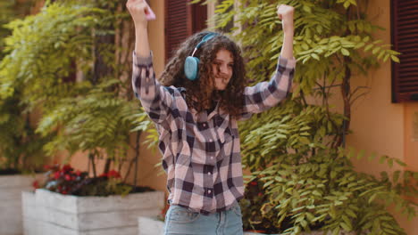happy young woman in wireless headphones listening favorite energetic music in urban city street