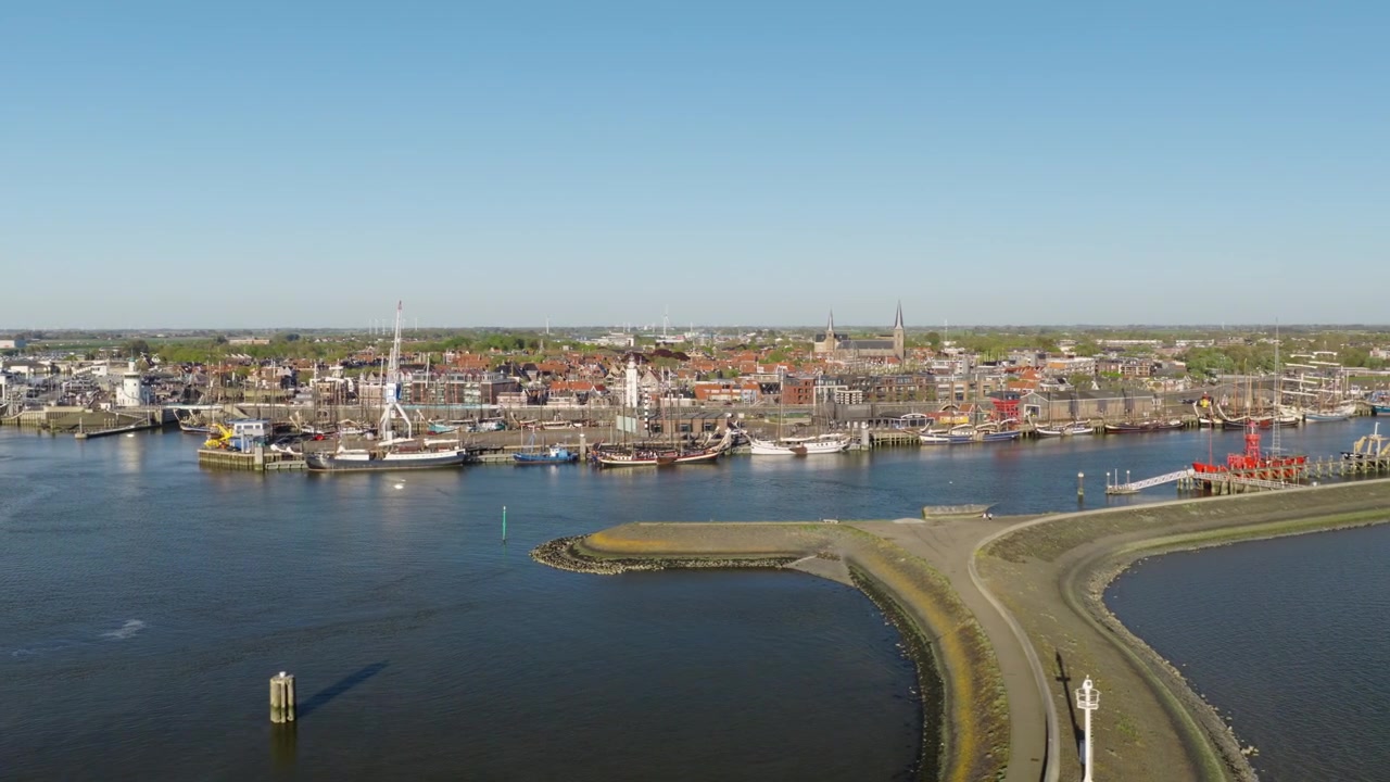 Harlingen havn åbner mod tidevandskanaler og Vadehavet, med både, kajer og den historiske by, der danner den kystnære baggrund i Friesland, Holland, parallaksebevægelse.
