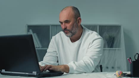 hombre de negocios pensativo sentado en un lugar de trabajo remoto con una computadora portátil. pensamiento profesional pensativo en la mesa en la oficina. cara de hombre de negocios enfocado mirando a su alrededor. retrato de hombre serio