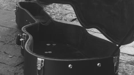 blanco y negro y vista de cerca de monedas cayendo en una caja de guitarra