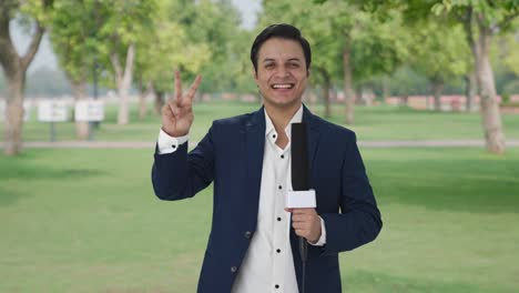 cheerful indian reporter showing victory sign