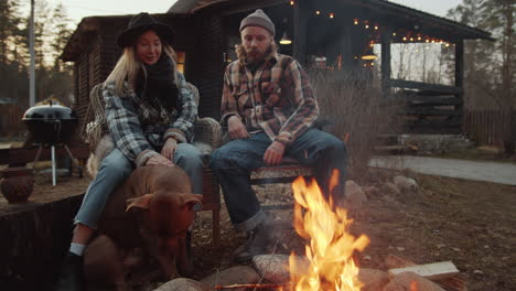 couple resting by bonfire and petting dog