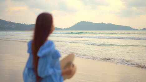 Woman-Stepping-in-Frame-on-Secluded-Beach-Puts-on-Sun-Hat