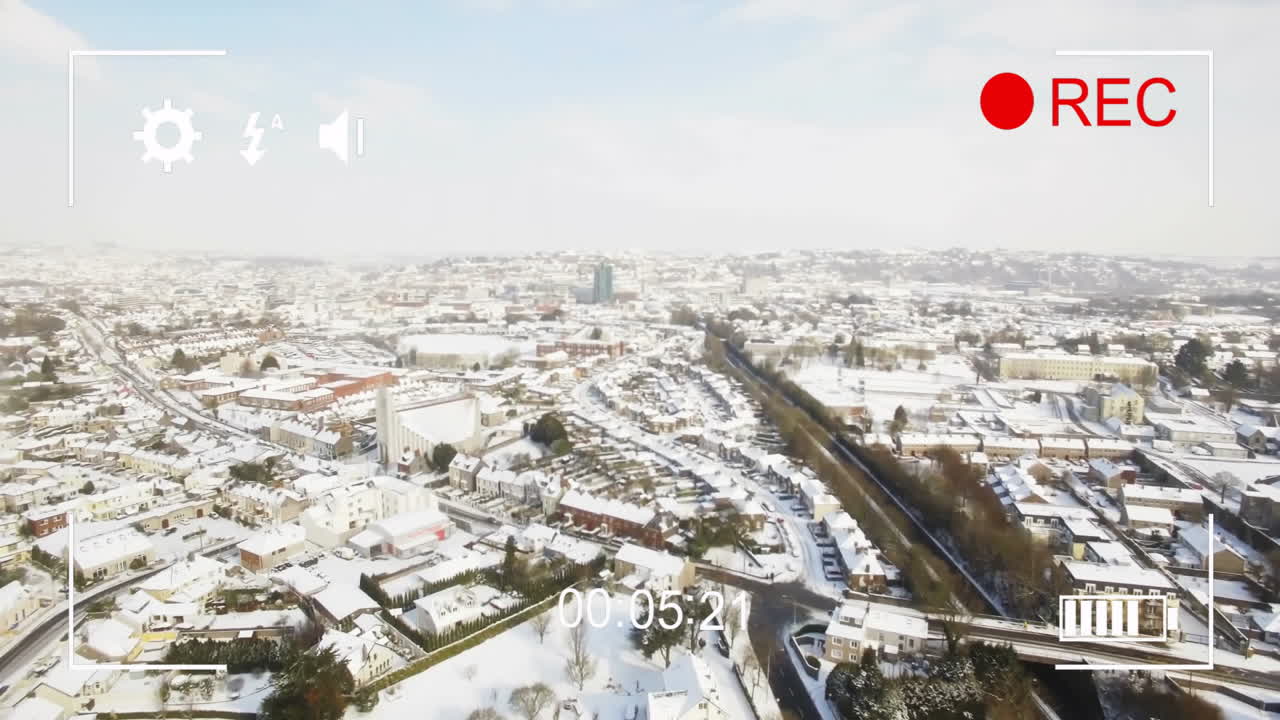 Aerial view of snowy cityscape with animation of video recording interface over it