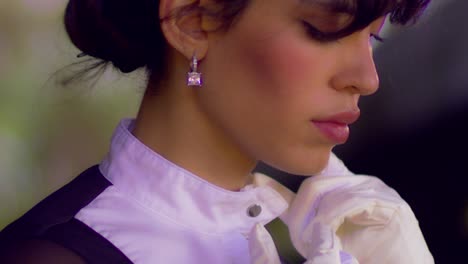 cinematic close up shot of a beautiful woman preparing herself for going horse riding while wearing a black and white horse riding outfit and diamond earrings, slow motion, slomo