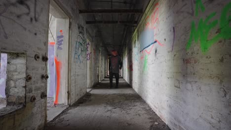 large shadowy male figure walking into light through dark corridor, slow-mo