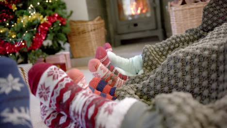 moviendo los pies de la familia en calcetines cálidos junto a la chimenea con el árbol de navidad, copiar el espacio, cámara lenta