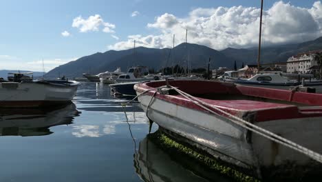 small, rustic boat at marina, mountains and clouds background, tivat, montenegro