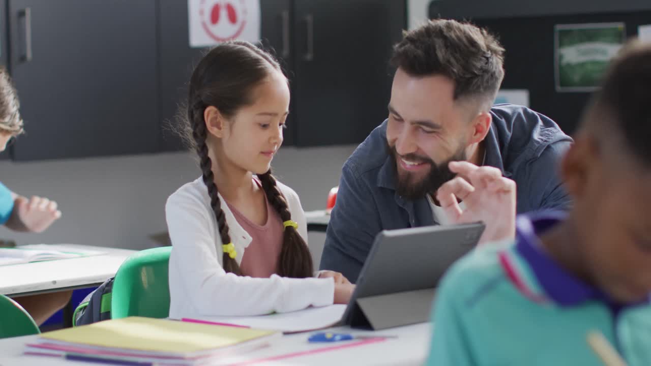 maestro masculino diverso y escolares felices usando tableta en el aula de la escuela