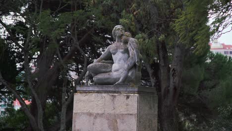 estatua en el parque de una mujer y su hijo con árboles en segundo plano.