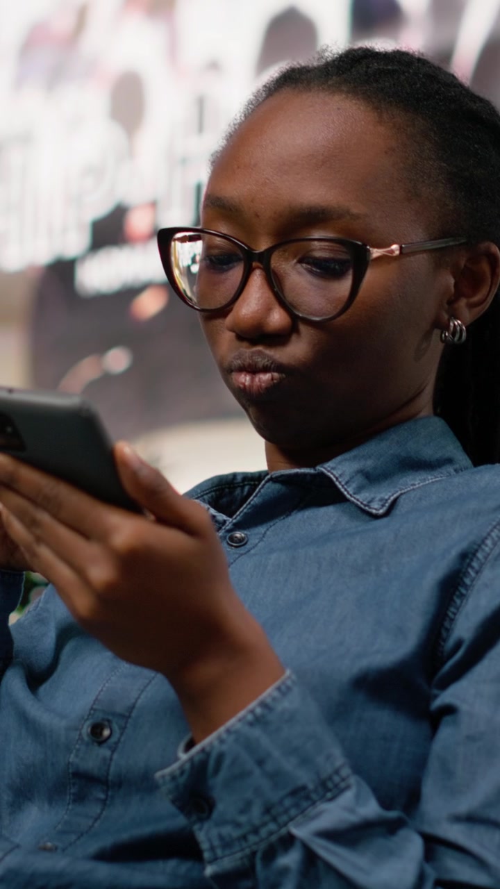 Vertical Video Black girl scrolling smartphone apps and relaxing on park bench