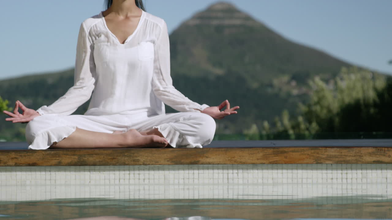mujer tranquila haciendo yoga junto a la piscina