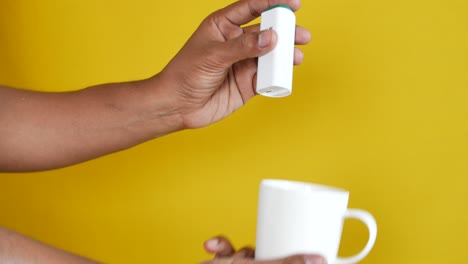 joven poniendo edulcorante artificial en el té