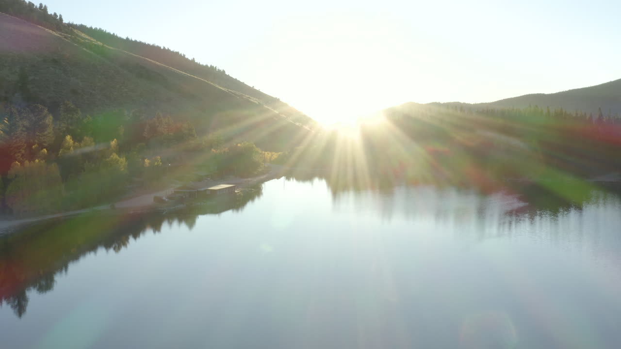 4K aerial drone footage of a sunrise over a lake in the Rocky Mountains of Colorado in the autumn or fall with changing aspen trees