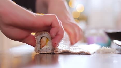 making sushi at home kitchen. woman hands rolling homemade sushi.