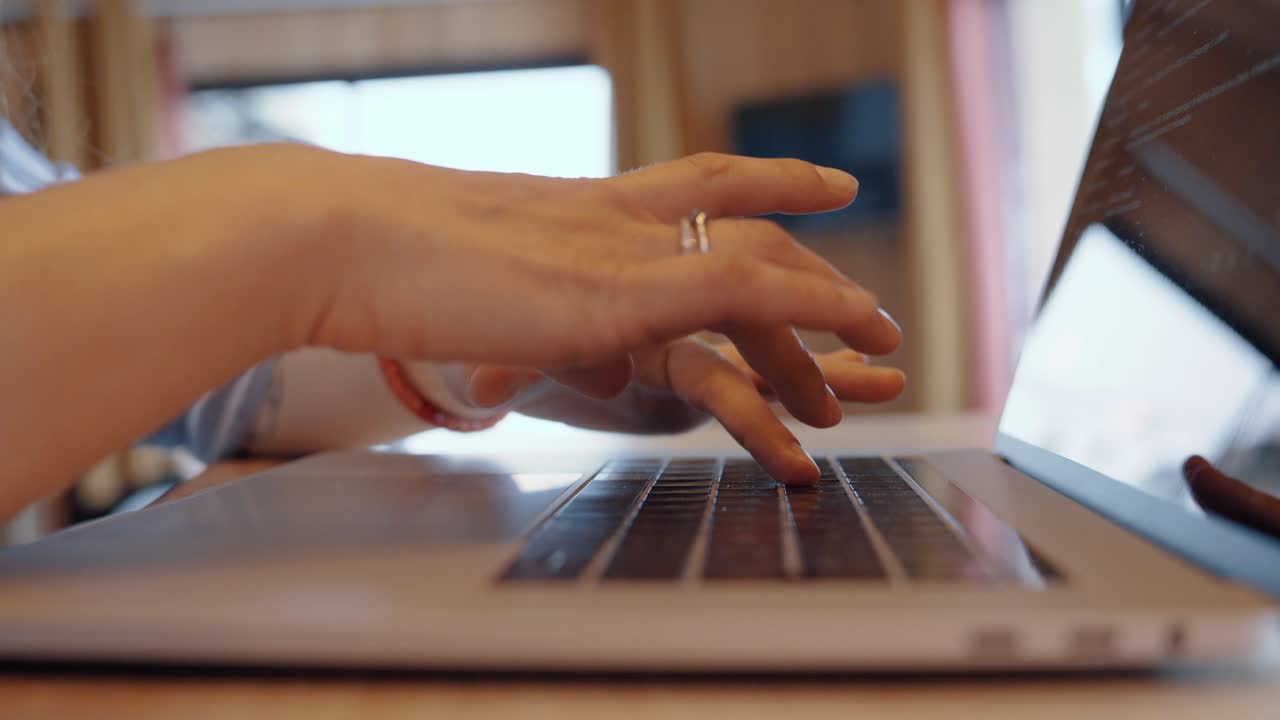 Traveling shot of woman typing on laptop, symbolizing focus, dynamic workspace, warm tones.