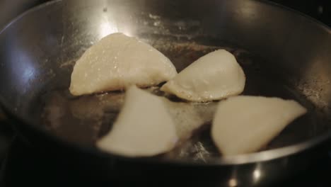 frying dumplings in an oil-heated skillet until crisp - close up shot