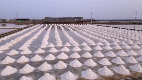 Panning-Shot-of-Sea-Salt-Piles-in-Phetchaburi,-Thailand