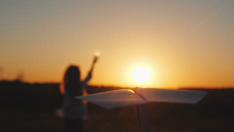 niña alegre está jugando con un avión de papel detrás de su padre corre - una vista en primera persona t