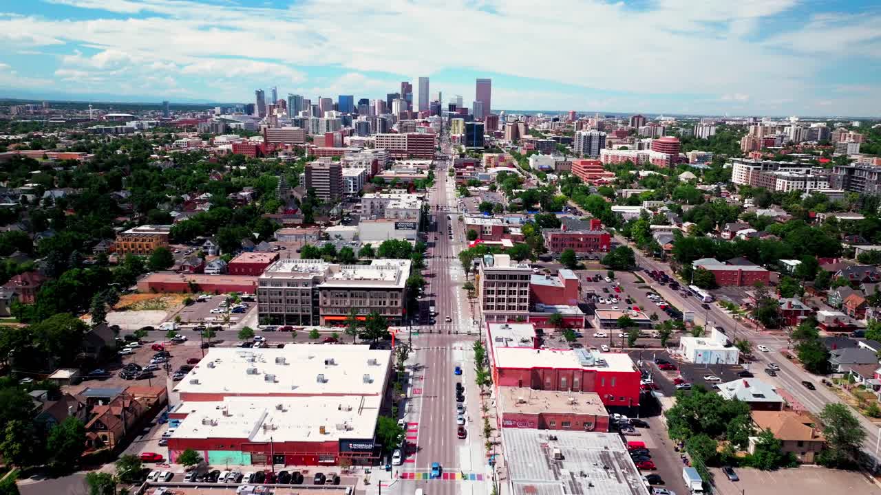 centro de denver sur de broadway street vista aérea de drones ciudad rascacielos paisaje negocios restaurantes tráfico coches peatones tráfico bicicletas cruzando la carretera verano tarde soleada nubes hacia adelante pan up