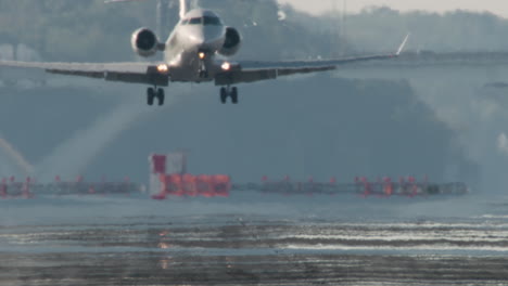 small jet lands with puff of smoke from tires with mirage on runway