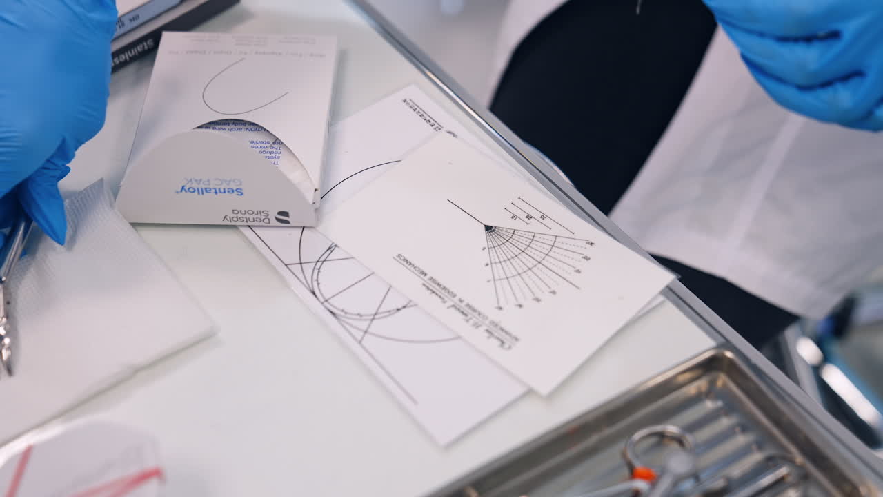 Female hands in blue latex gloves take the metal instrument and stainless wire. Orthodontic practice concept.