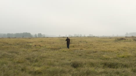 documentalista masculino tomando fotografías en un pastizal de niebla, otoño, chequia