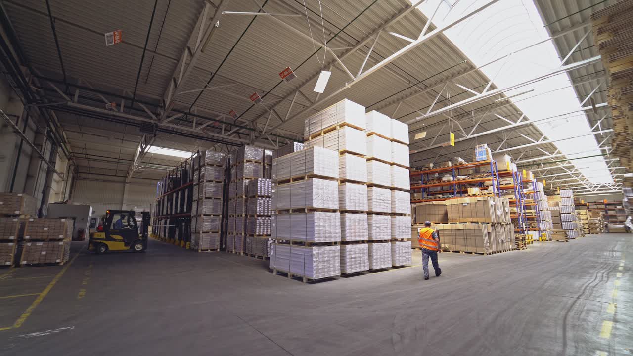 Storekeeper deploys the loader and lifts the hydraulic forks to picks up the cargo on the shelf in the storage.