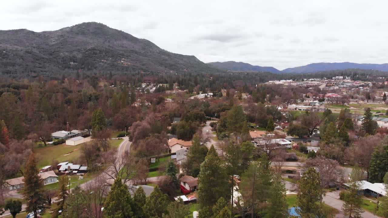 toma aérea de un barrio en un pequeño pueblo de montaña, panorámica hacia arriba para revelar montañas y nubes de tormenta