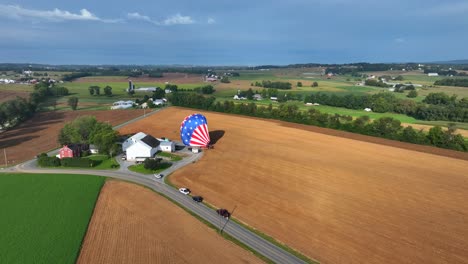 aerial birds eye shot of american hot air balloon landing on wheat field in countryside area of pennsylvania, usa