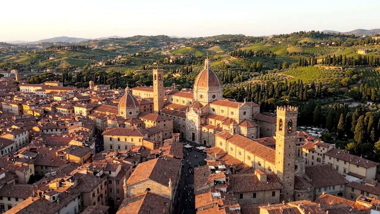 Vedute aeree mozzafiato di architettura storica circondata da rigogliose colline verdi al tramonto in un incantevole borgo toscano