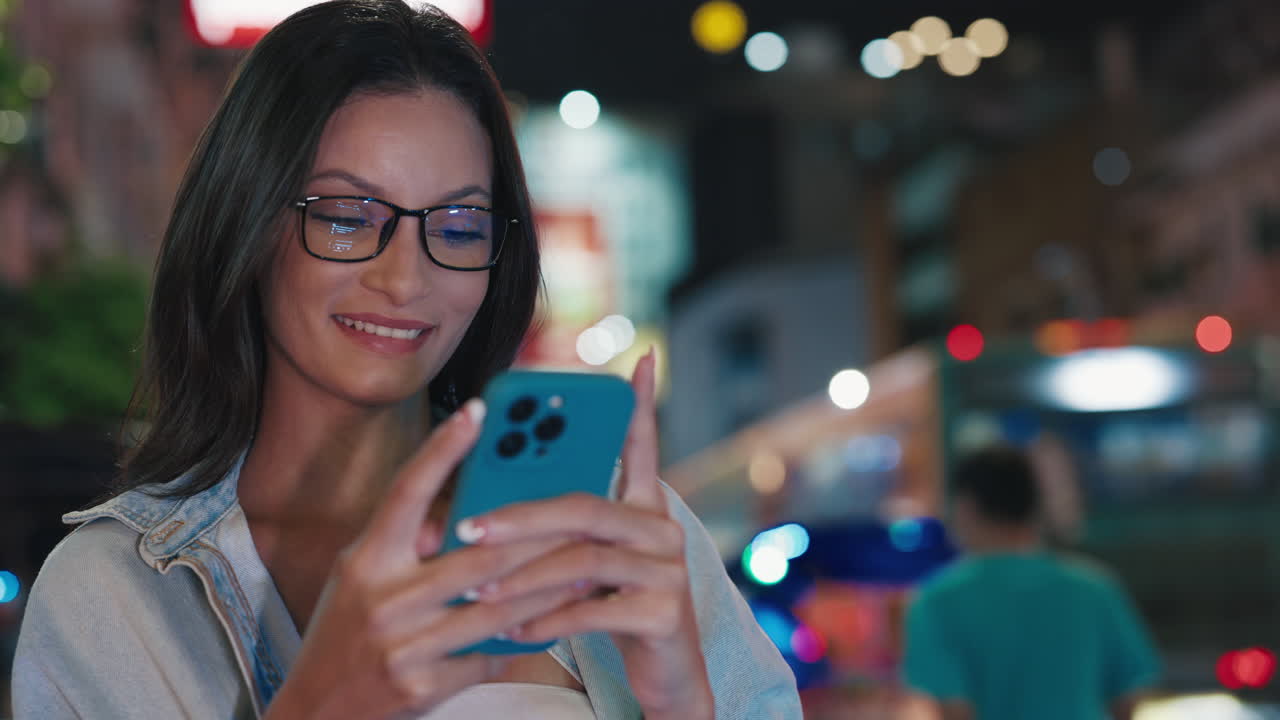 Woman using phone at night in a city