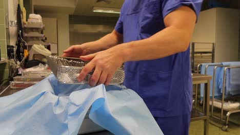 an employee of a surgical department packs cleaned instruments into a container