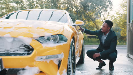 man washing a yellow sports car