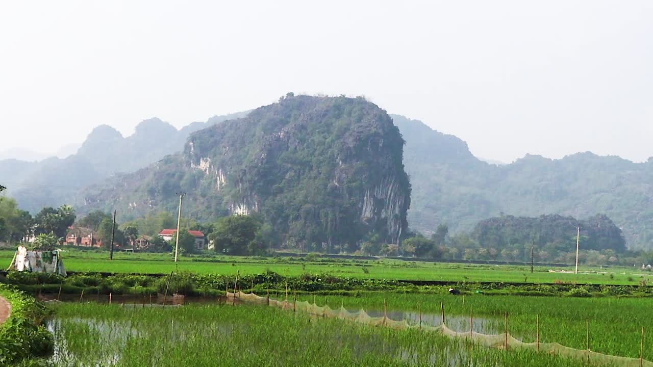 A serene path winds through lush fields with a reflective waterway and distant mountains.