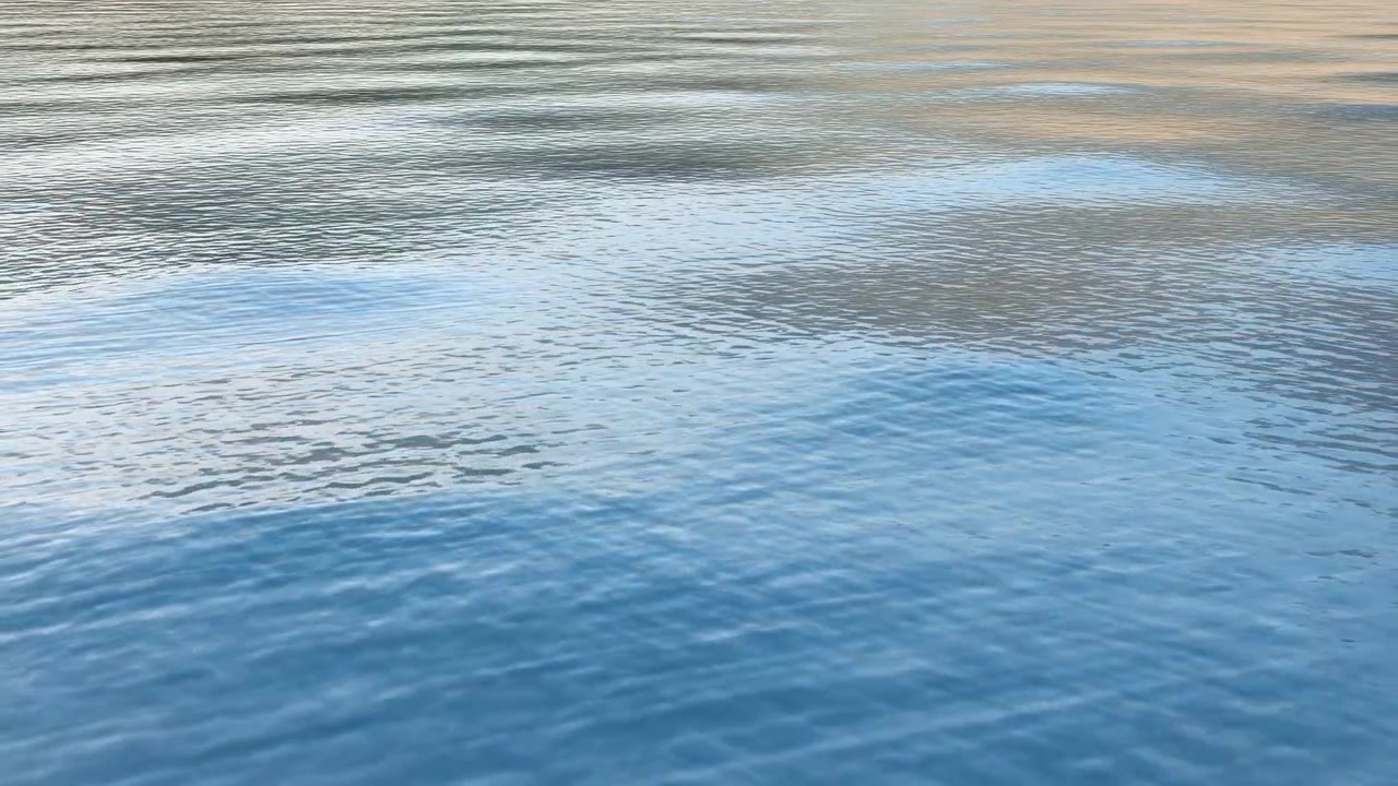 穏やかな青い水面にはさざ波が立ち、空がかすかに映り込み、ゆっくりと波打つような動きで、質感がある
