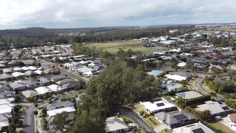 Drone-flying-over-a-residential-estate-revealing-private-homes,-streets-and-solar-panels-on-many-homes