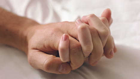 Couple,-love-and-trust-holding-hands-while-in-bed