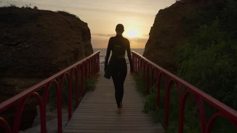 woman practicing yoga on a coastal bridge at sunrise