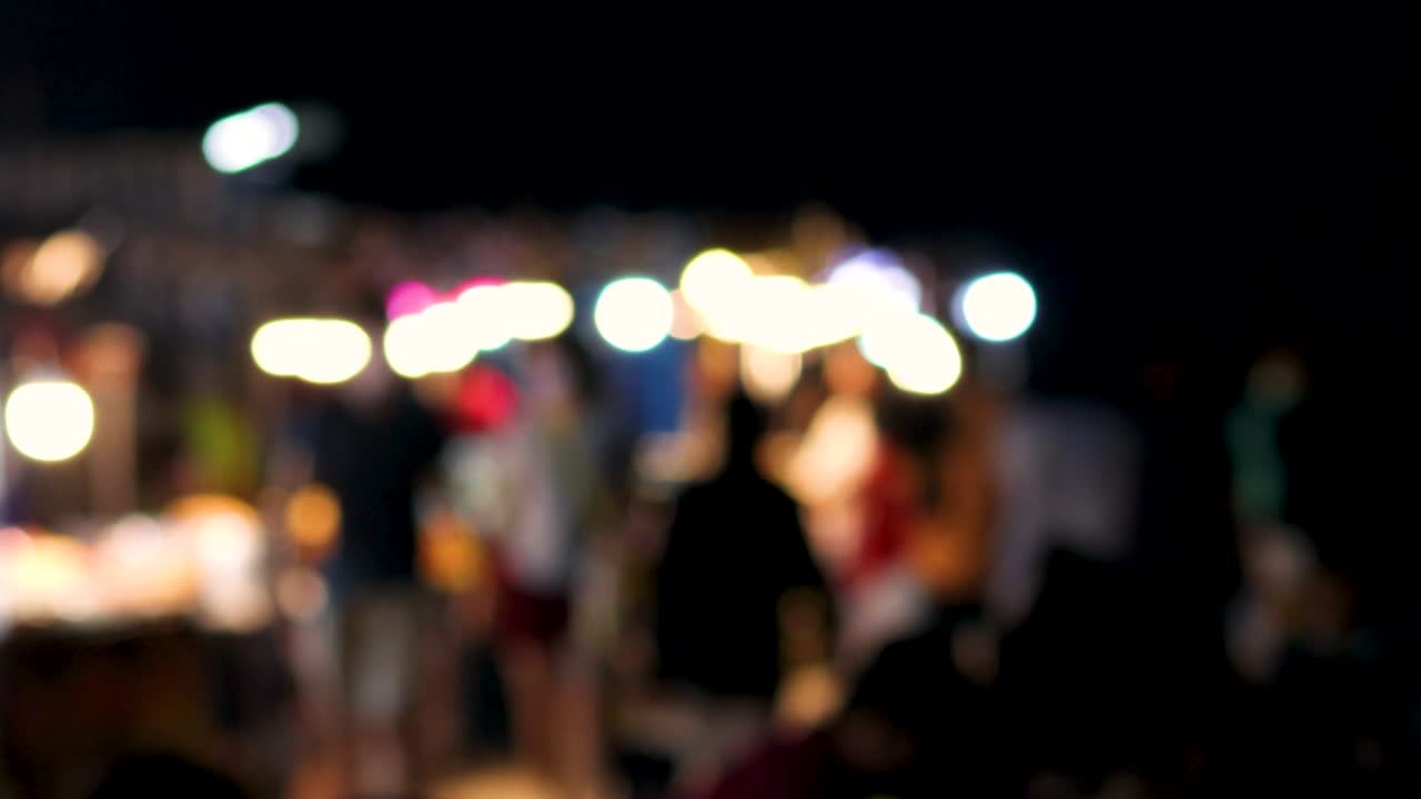 borrosa de personas vagando por el mercado de pulgas en busca de comida por la noche.