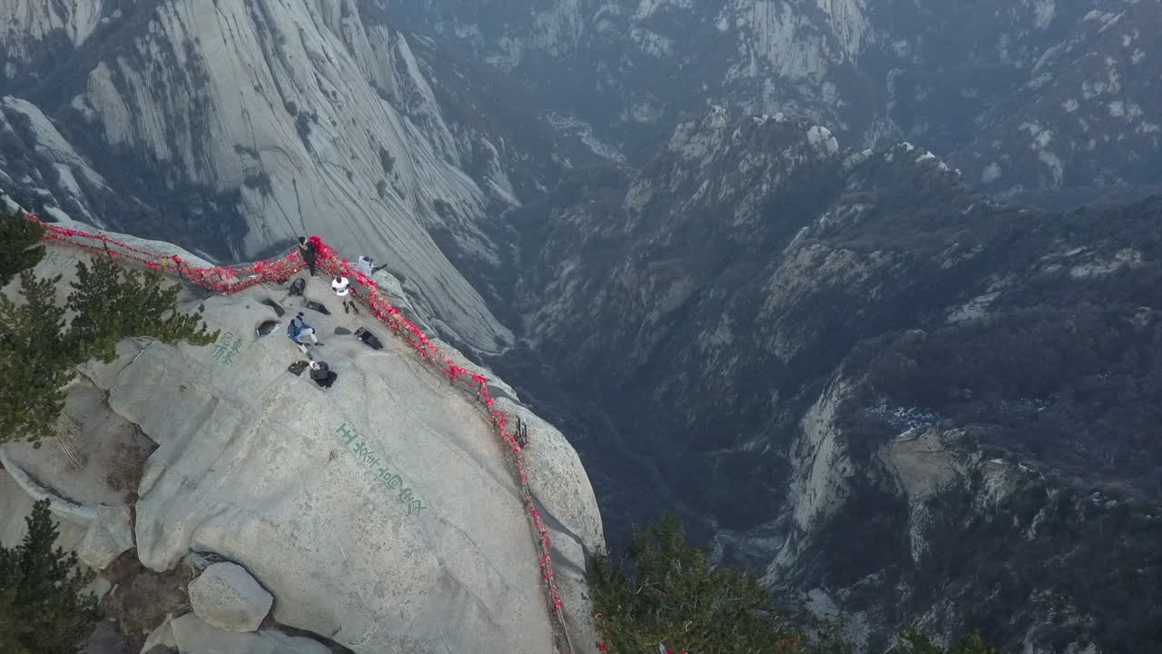 가파른 화강암 절벽 가장자리에 앉아있는 관광객을 드러내는 공중 기울기