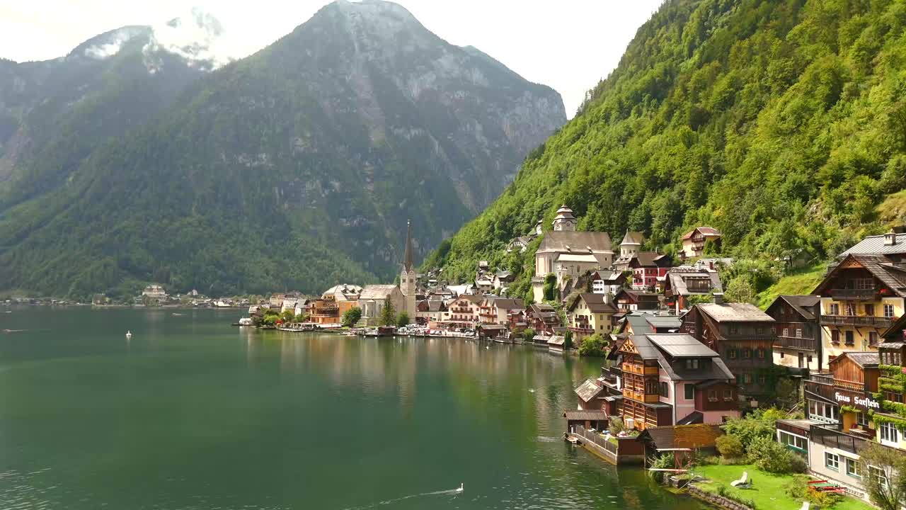 Aerial view of Hallstatt, Austria, captured by drone, showcasing its picturesque lakeside homes, majestic mountains, and the unique charm of this enchanting alpine village.