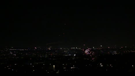 Fuegos-Artificiales-Disparados-En-Primer-Plano-Con-Más-Fuegos-Artificiales-Sobre-La-Ciudad-En-Segundo-Plano