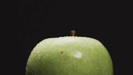 Micro-video-of-close-up-of-green-apple-with-copy-space-on-black-background