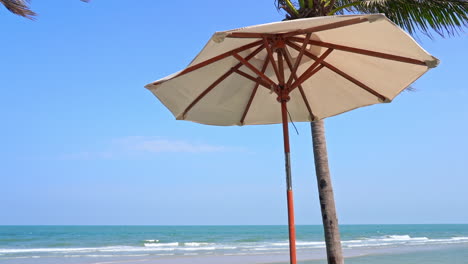 One-beach-Sunshade-and-coconut-palm-seafront-at-island-beach-with-low-tides-rolling-on-sand