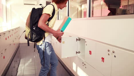 handsome student putting notebooks in his locker